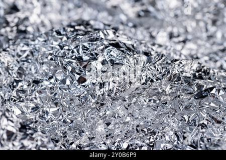crumpled thin aluminum foil reflecting light, thin foil for use in cooking crumpled from different sides, there may be dust and crumbs from food on th Stock Photo