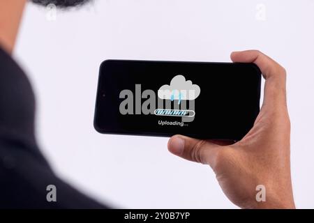 Phone data backup and cloud data storage concept. Man using a smartphone to upload data to cloud storage. Stock Photo