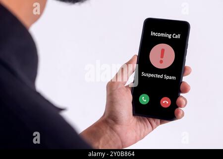 Hand holding a smartphone with incoming call from unknown caller on the screen. Spammer incoming call concept. Stock Photo