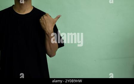 Young man looking and pointing finger to the side to an empty mock-up space Stock Photo