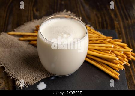 Thin and long bread sticks made of wheat flour and a glass of milk , sweet wheat pastries on the table with cow 's milk Stock Photo