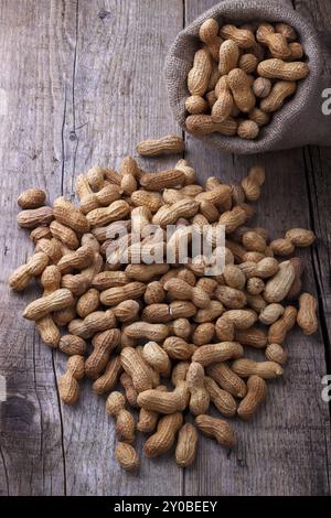 Peanuts in a burlap sack on wooden background Stock Photo
