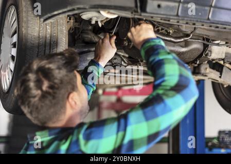 Portrait of mechanic repairing with a wrench a lifted car Stock Photo