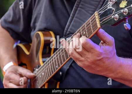 Detail of guitarist's hands and his black electric guitar at an outdoor jazz presentation Stock Photo