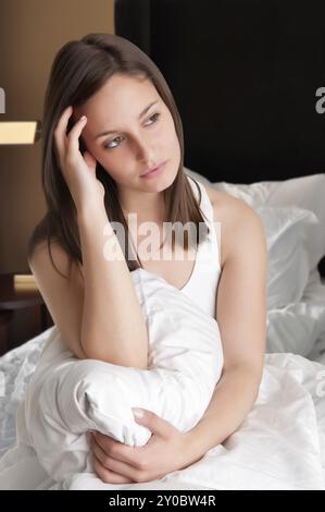 Woman sitting on a bed, waking up Stock Photo
