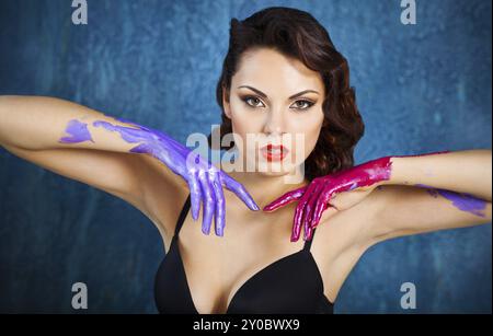 Portrait of a beautiful young woman with bright make up and colored splashes hands Stock Photo