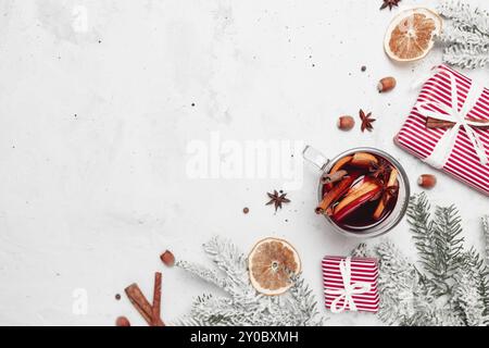 Christmas flat lay top view on white gray concrete background table with glass cup or mug of Mulled Wine, present red gift boxes, decorations, cinnamo Stock Photo