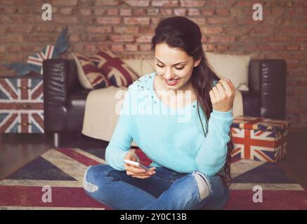 Young beautiful woman sitting with smart phone. Toned picture Stock Photo