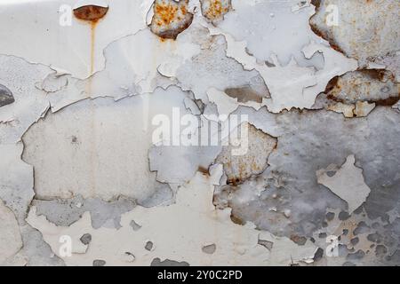 Peeling white paint and rust stains on a abandoned car, close up abstract Stock Photo