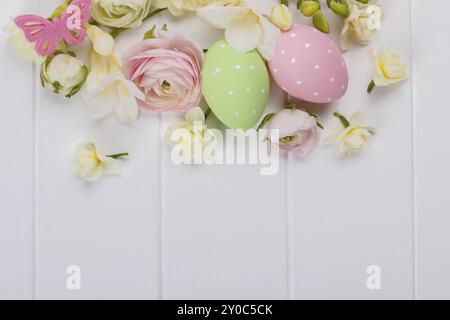 Easter eggs with ranunculus flowers on white wooden background Stock Photo