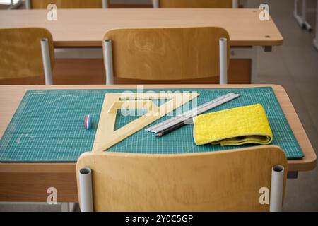 Classroom desk showcasing math tools such as a ruler and set square, along with an eraser and cleaning cloth on a cutting mat. Stock Photo