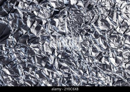crumpled thin aluminum foil reflecting light, thin foil for use in cooking crumpled from different sides, there may be dust and crumbs from food on th Stock Photo