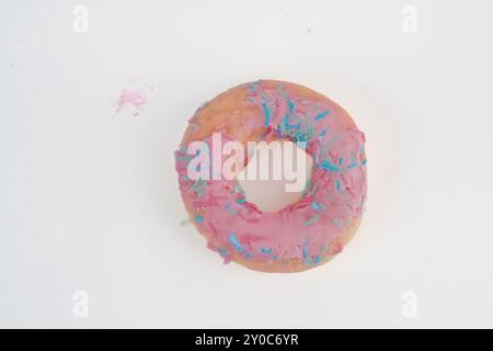 A pink donut with sprinkles on top. The donut is sitting on an isolated white background. Stock Photo