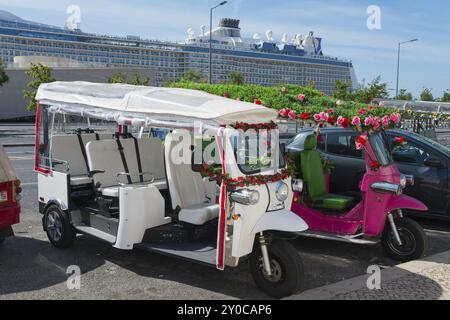 Two decorated tuk-tuks stand side by side, one white, the other pink, a large cruise ship can be seen in the background, Lisbon, Lisboa, Portugal, Eur Stock Photo