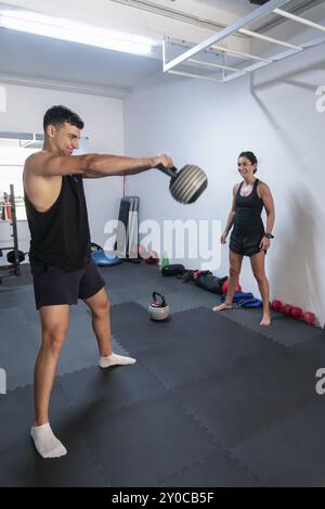 A gymnast is doing exercises with weights while his trainer watches and supervises him Stock Photo