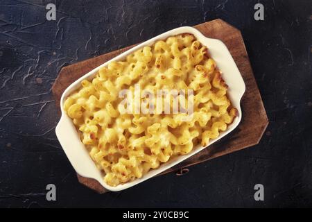 Macaroni and cheese pasta in a casserole, overhead shot on a black background. Traditional American comfort food Stock Photo