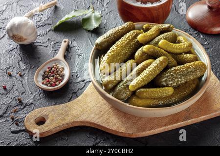 Pickled cucumbers with salt, pepper, garlic, and bay leaf. Fermented food. Homemade canned gherkins on a black slate background, Food photography, Foo Stock Photo