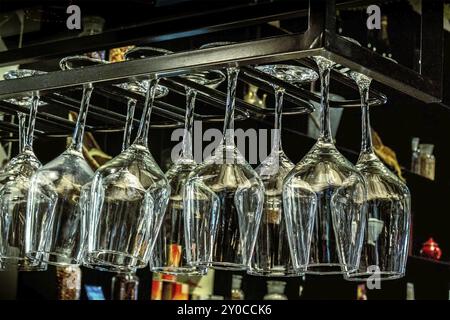 Wine glasses hanging from a stemware rack in a bar Stock Photo