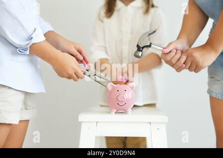 Kids with screwdriver, pliers and hammer by the pink pig piggy bank on a white background Stock Photo