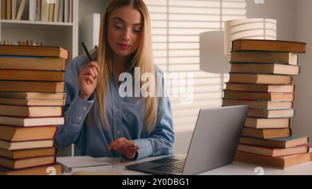 Caucasian student happy smiling girl woman studying with laptop and books homework learning online knowledge prepare for test exam study at library Stock Photo