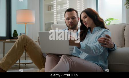 Caucasian couple using laptop app choose goods buying clothes in online web store internet shop shopping together choosing travel tour man woman love Stock Photo