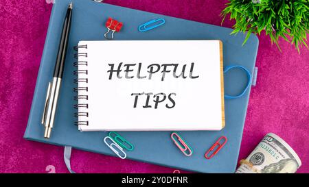 Helpful Tips words in a notebook in front of an abstract background. Stock Photo
