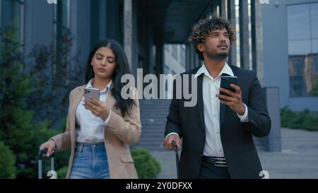 Two business coworkers gadget addict Arabian businesswoman walking city airport terminal using mobile phone Indian businessman browsing typing Stock Photo