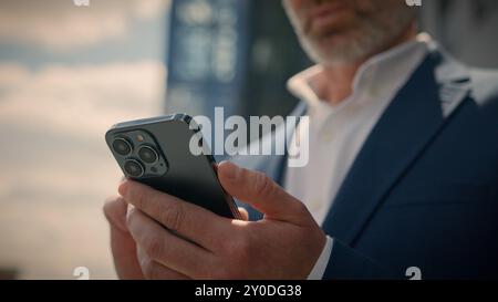 Close up senior business man pensive think problem solution looking at mobile phone in city thoughtful businessman mature entrepreneur elderly Stock Photo