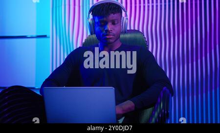 Hacker programmer computer worker gamer African American man in headphones male guy typing laptop online data internet security gaming play video game Stock Photo