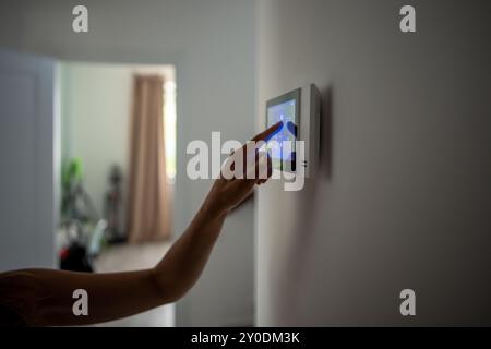 Closeup hand using smart home panel, touching screen with connected appliances device on wall. Stock Photo