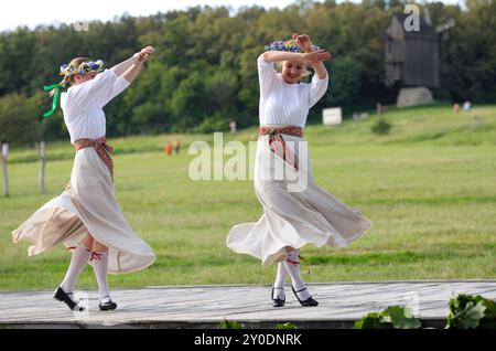 Two young women in national Latvian costumes dancing celebrating Jan Day, midsummer. Days of Latvia culture. June 18, 2021. Pyrogove, Kyiv, Ukraine Stock Photo