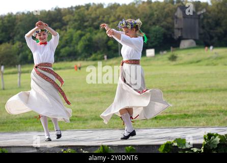 Two young women in national Latvian costumes dancing celebrating Jan Day, midsummer. Days of Latvia culture. June 18, 2021. Pyrogove, Kyiv, Ukraine Stock Photo