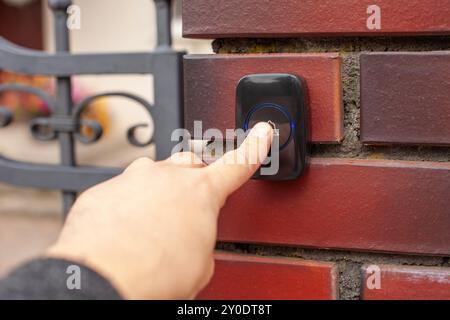 Hand Pressing Doorbell on Red Brick Wall Stock Photo