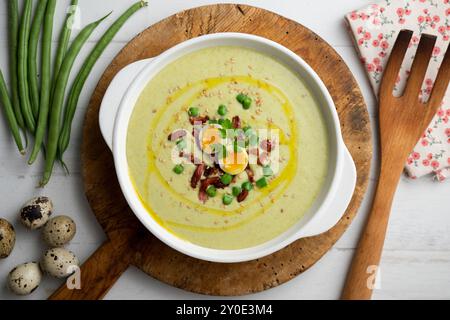 Cream of green beans with Iberian ham and quail egg. Top view table with  decoration. Stock Photo