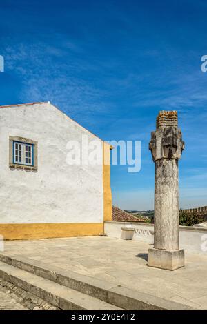 Old stone cross monument.Óbidos, a walled Portuguese town, a tourist destination in the Lisbon region. Charming and attractive city in Portugal. Stock Photo