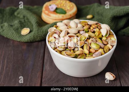 White bowl filled with shelled and unshelled pistachios on a wooden table,crunchy pistachio nuts as snack Stock Photo