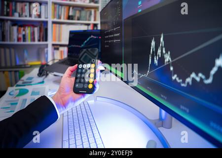 Businessman holding calculator. Financial results stock market. Monitors displaying graphs. Home office interior. Blue light. Stock Photo