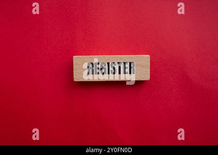 Register message written on wooden block with redbackground. Conceptual register symbol. Copy space. Stock Photo
