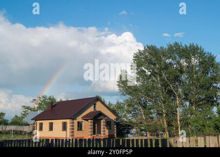 Rainbow over brick house at countryside - rural landscape Stock Photo