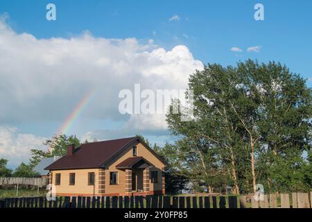 Rainbow over brick house at countryside - rural landscape Stock Photo