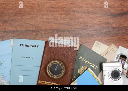 High angle shot of a travel still life. Items include: passport, wallet, post cards, camera, pictures, maps, and itinerary folder on a wood desk. Hori Stock Photo