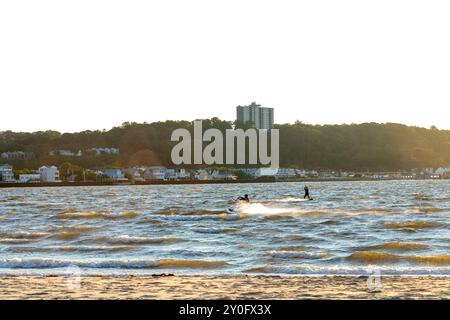 Sandy Hook, New Jersey - August 21, 2024: Kiteboarders take to the water as the sun sets over Sandy Hook on a gorgeous summer's night Stock Photo