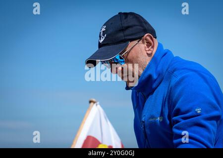 Close-up of middle-aged nautical style man with mirrored glasses wearing a blue fleece sweatshirt and a baseball cap Stock Photo