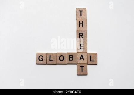 Close-Up of Wooden Tiles Forming Crossword Puzzle with Words "Global" and "Threat" – Concept of Worldwide Security Concerns Stock Photo
