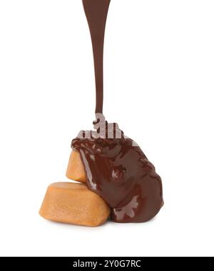 Pouring delicious melted chocolate onto caramel candies isolated on white Stock Photo