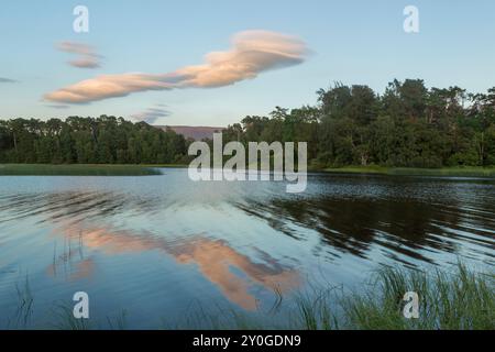 Lenticular cloud forming over Cairngorm mountain range viewed from across Loch Insh in warm evening light Stock Photo