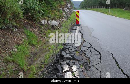 A damaged asphalt road with yellow-red traffic beacon in Norway Stock Photo