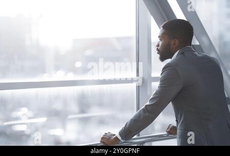 Wait for Flight. Afro Businessman Looking Through Window Stock Photo