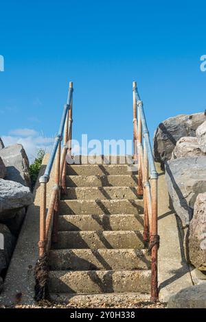 concrete steps with rusty metal handrail, blue sky background Stock Photo