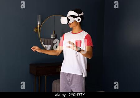 Using VR headset, asian man exploring virtual reality experience in modern room Stock Photo